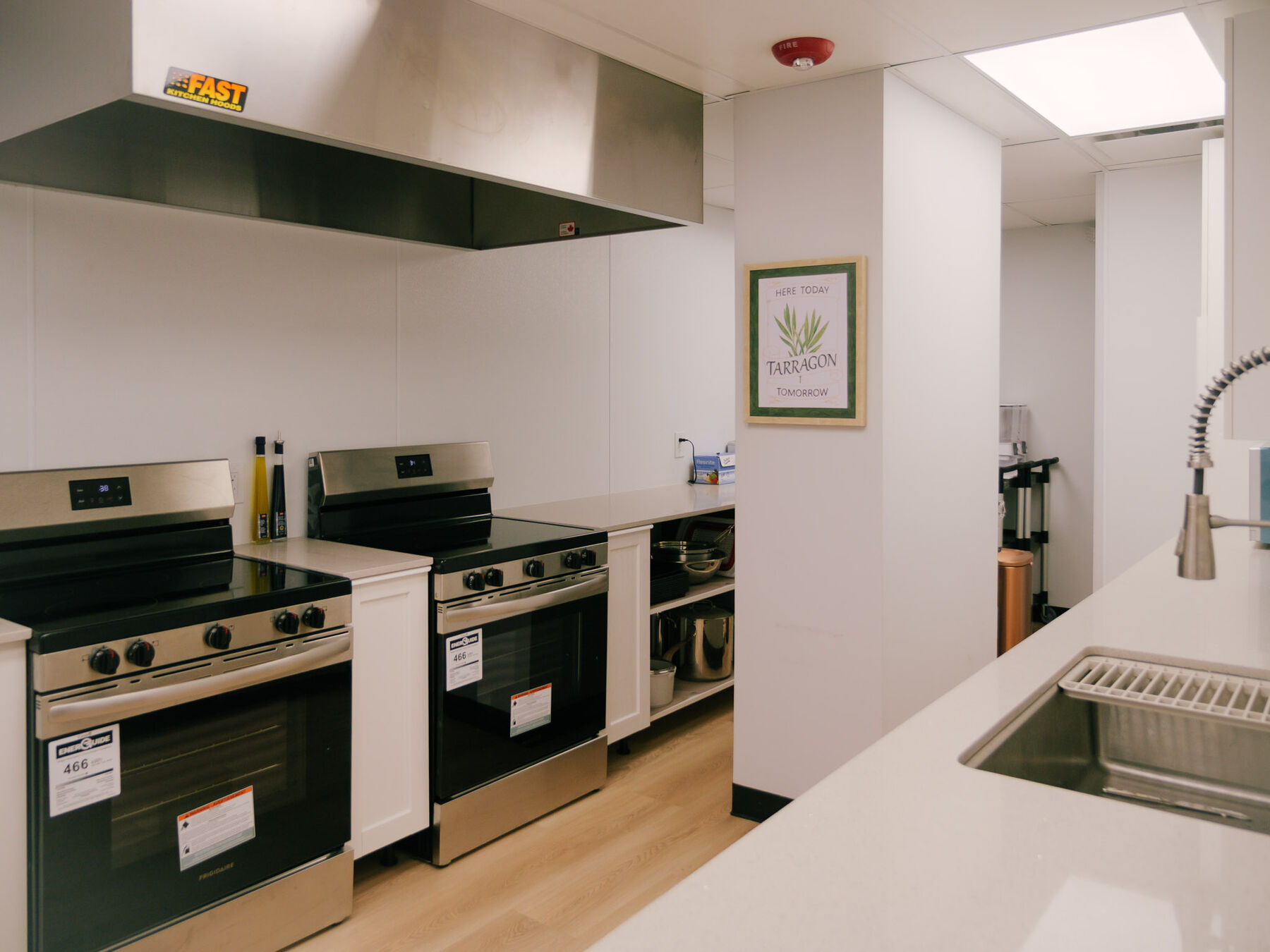 A commercial kitchen with two full ranges beneath a stainless extraction hood.