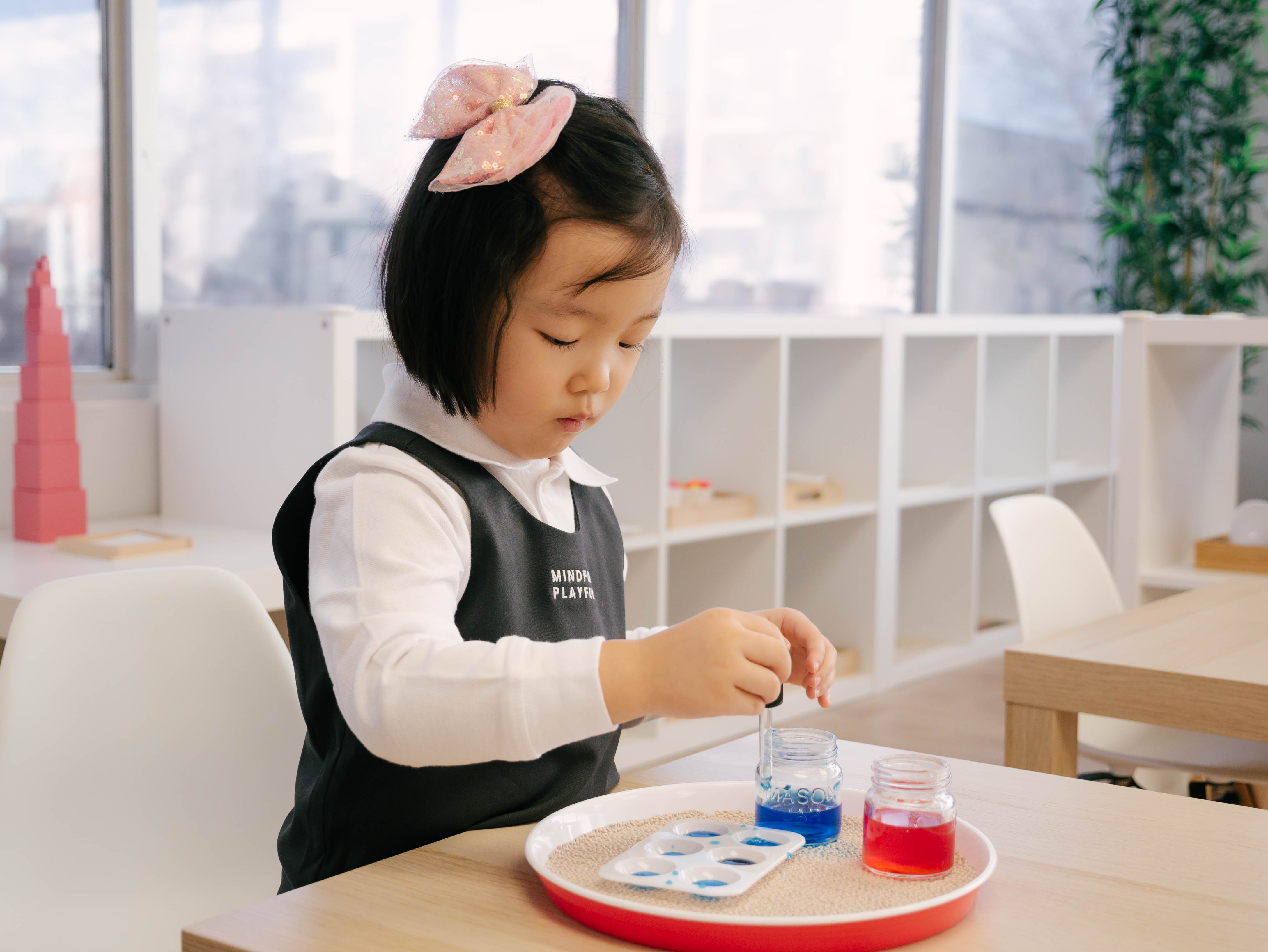 Girl engaged in color mixing Montessori activity