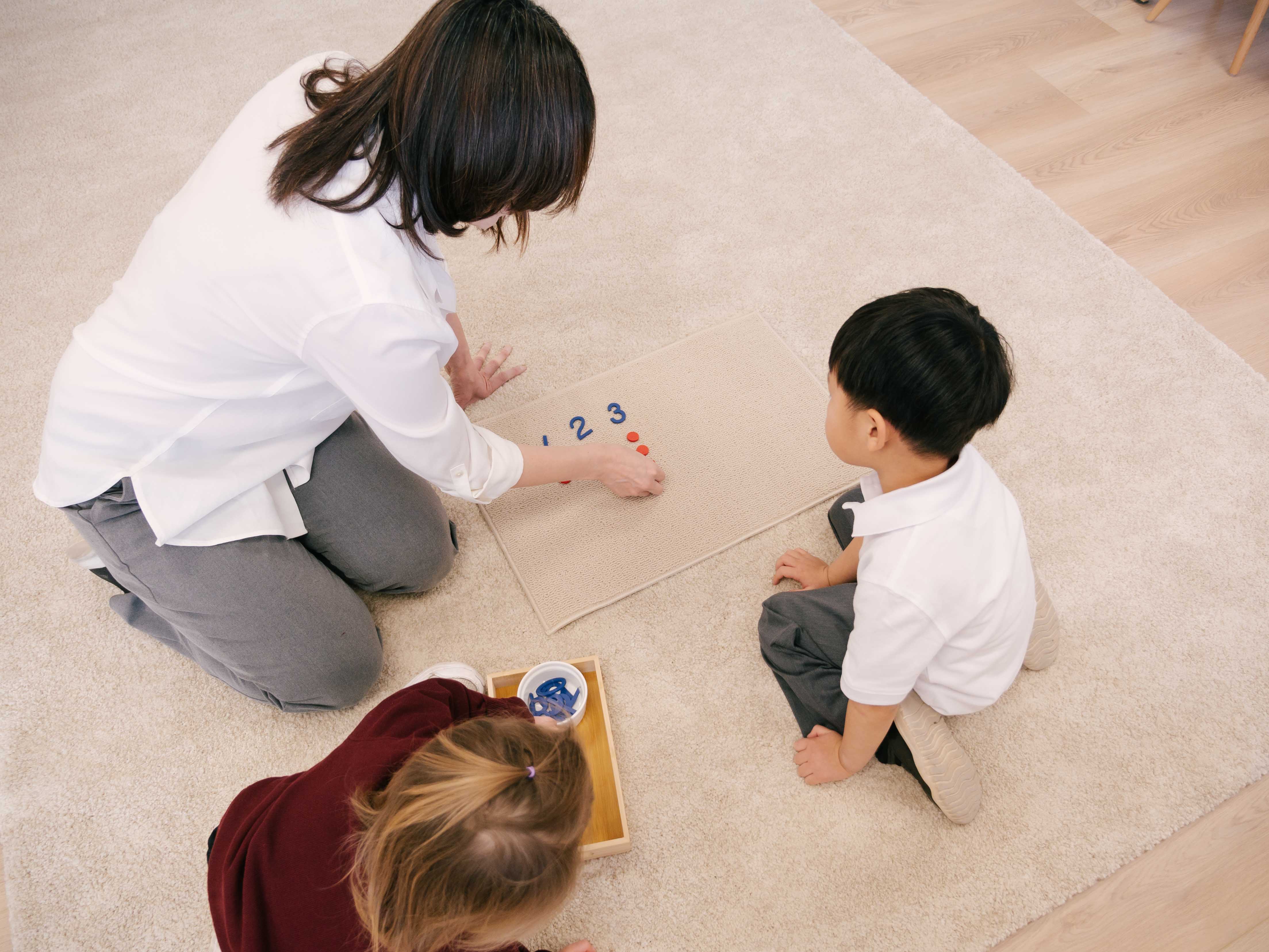 Teacher counting numbers with children on the floor