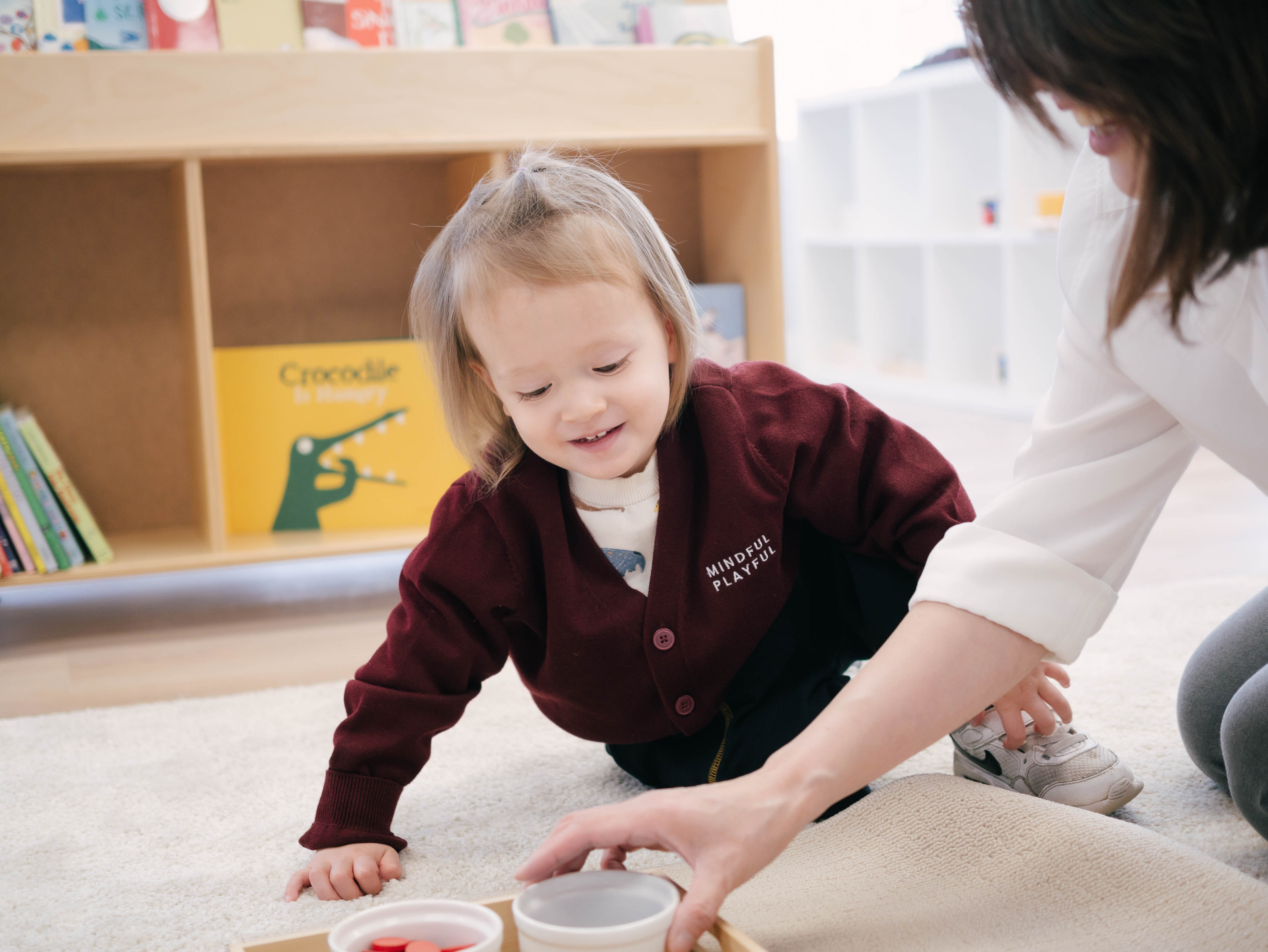 Toddler and teacher engaged in a hands-on learning activity at Mindful Playful preschool
